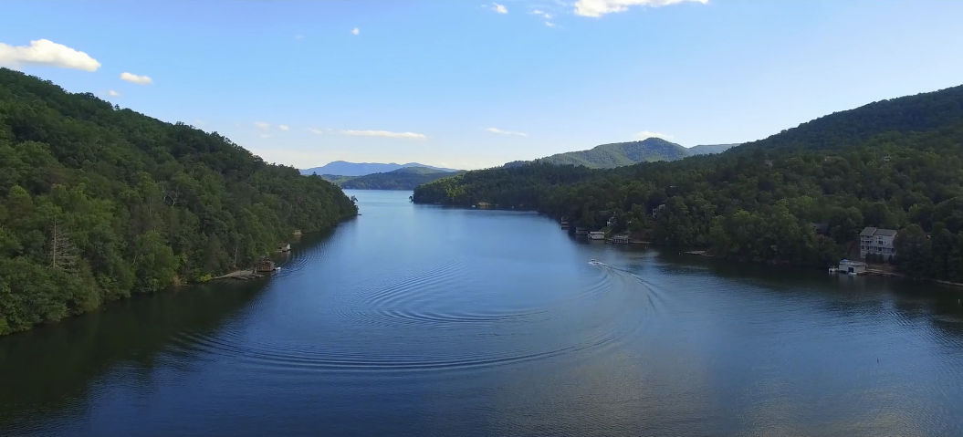 Aerial view of a serene lake nestled between lush tree-covered mountains