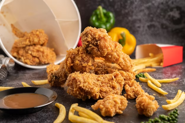 Spilled fried chicken, fries, and a toppled bucket on a table